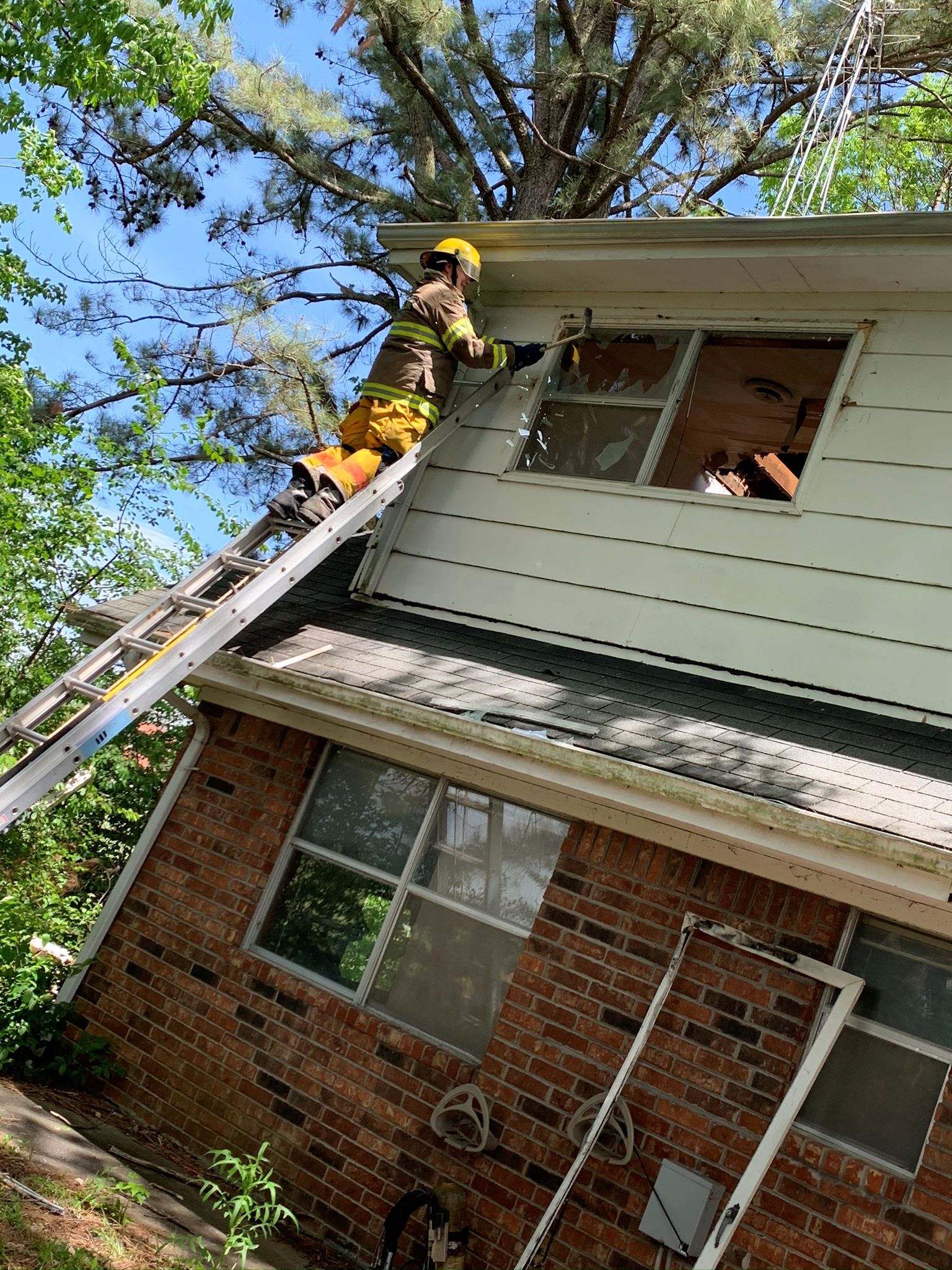 Picture of a firefighter climbing up a ladder into a house